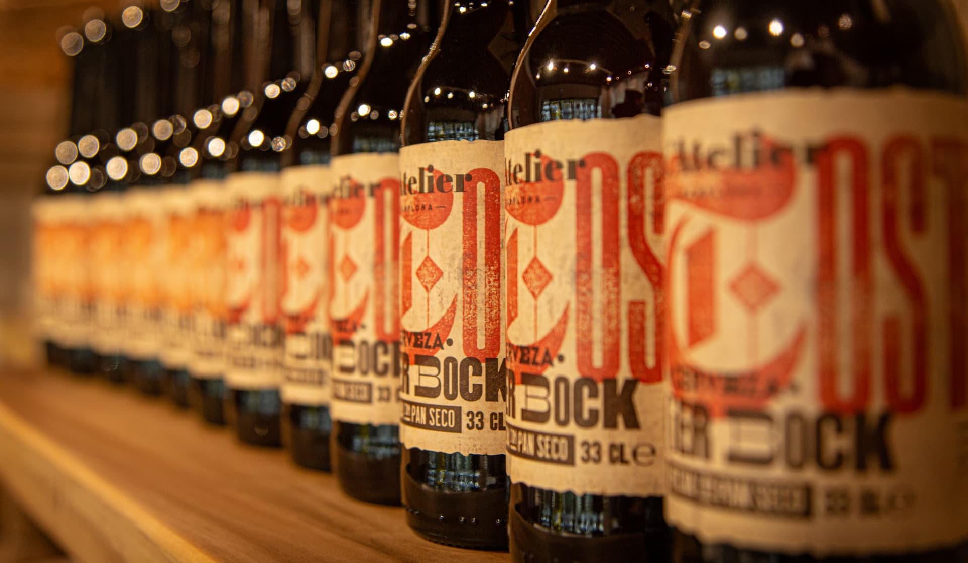 Imagen de varias cervezas una a continuación de otra y detalle del diseño de la etiqueta de Cervezas L'Atelier con la tipografía corporativa Drunken Master