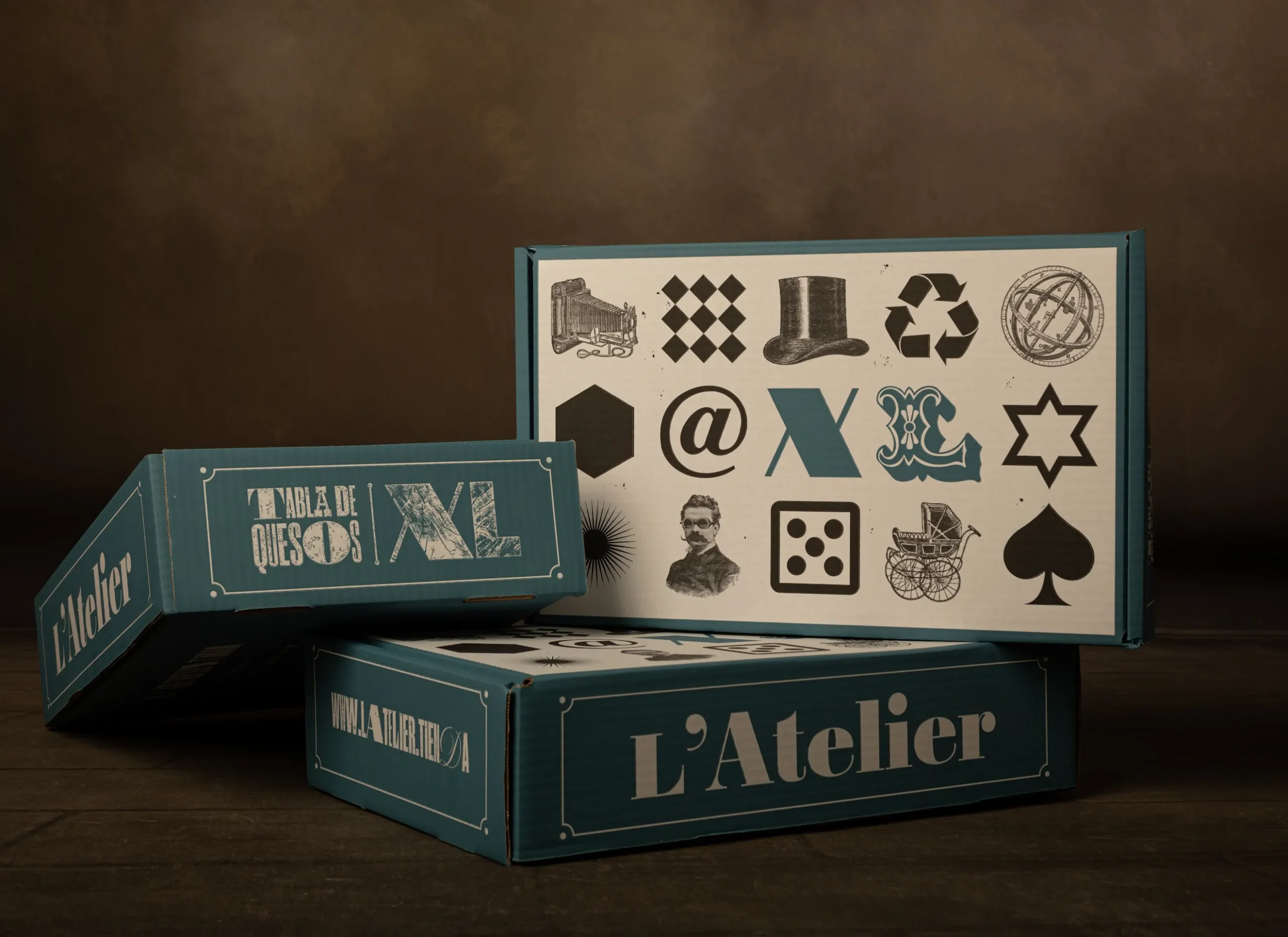 Imagen de varias cajas apiladas con detalle azul con el diseño de packaging de quesos L'Atelier con tipografía e iconografía de letterpress