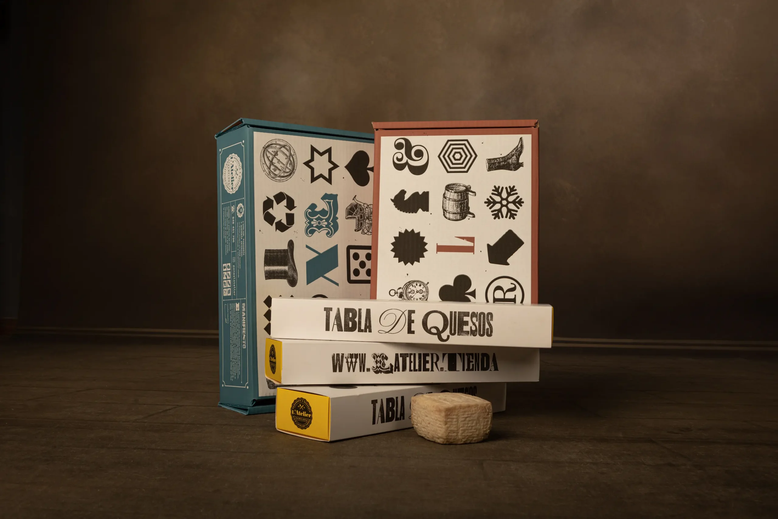 Imagen de varias cajas frontales con el diseño de packaging de quesos L'Atelier con tipografía e iconografía de letterpress