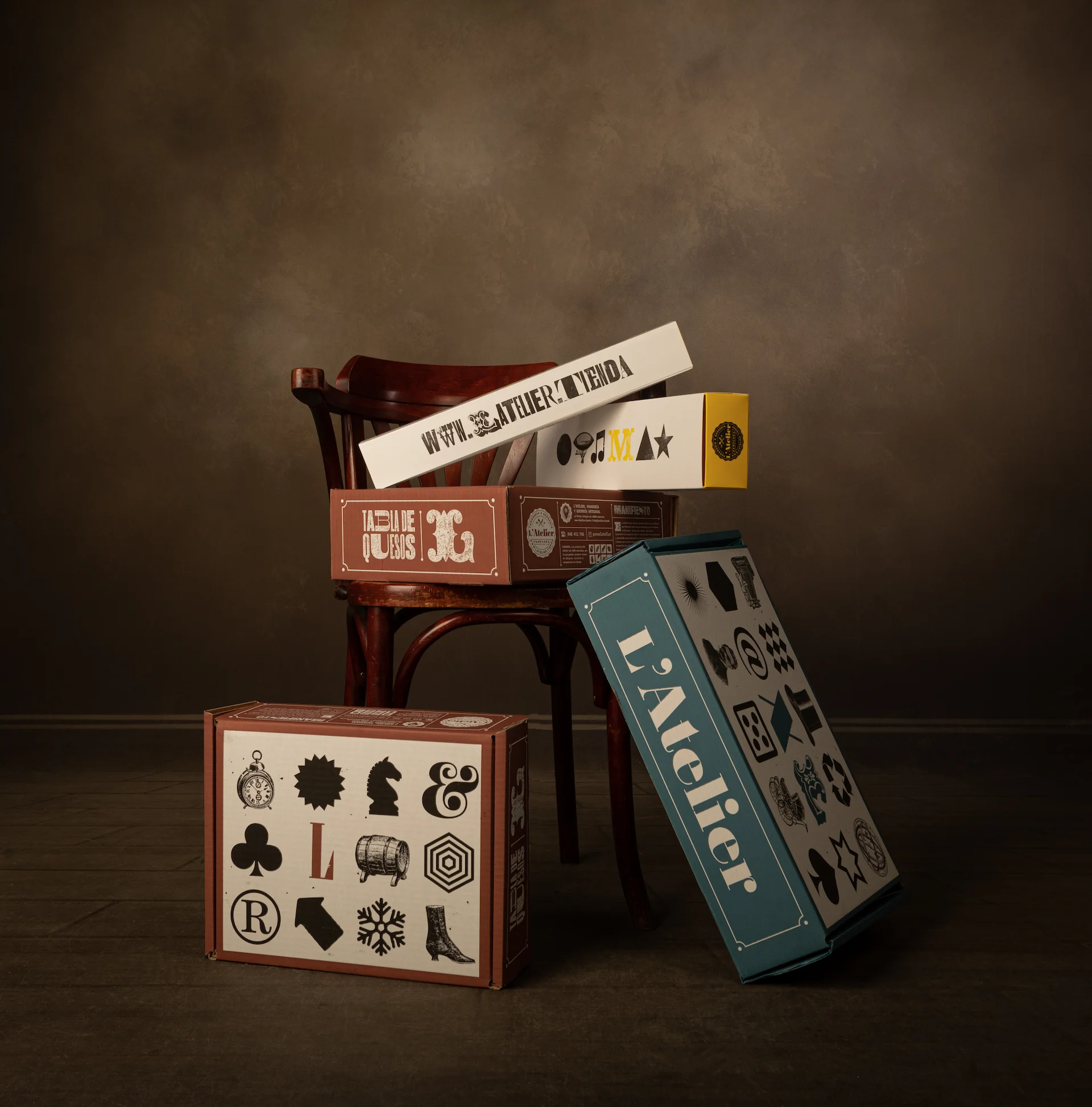 Fotografía de varias cajas apiladas con el diseño de packaging de quesos L'Atelier con tipografía e iconografía de letterpress